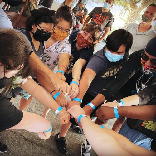 group of students putting hands together, all wearing wristbands